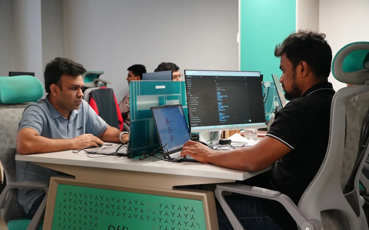 Two Girmairi engineers reviewing work face-to-face at a shared desk in the Dhaka, Bangladesh office